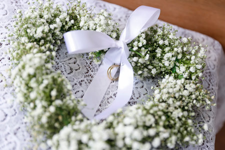 white bow wedding rings wrapped in flower arrangement - selective focusの写真素材
