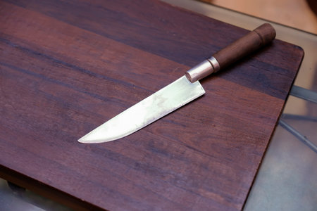 Knife with shiny blade on wooden countertop, ideal for kitchen use, precise cutting, and rustic settingの写真素材