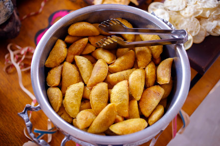 Appetizing image of golden cornmeal pastel in metal bowl with fresh angu pastries on rustic wooden...