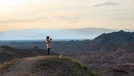 Woman photographer taking pictures at sunset in the mountains. Beautiful landscape with mountains.