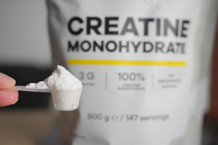 Heaped Scoop of Creatine Powder with Bag in Backgroundの写真素材