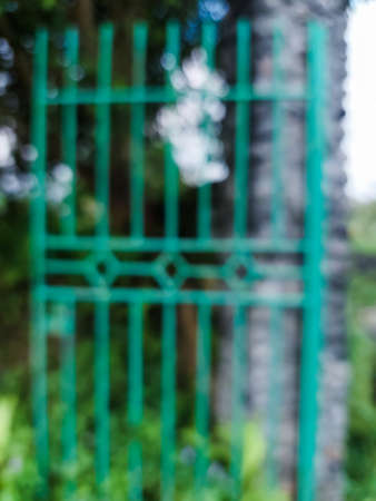 blurred photo of green swing gate and old stone gate