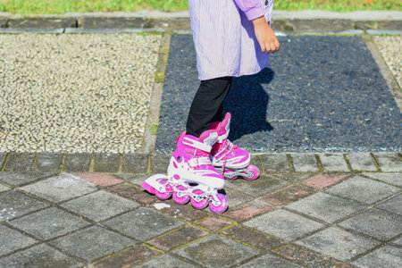 Little pretty girl on roller skates in helmet at a park.の写真素材
