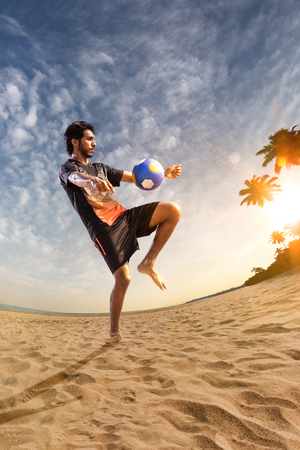 Beach soccer player in action. Sunny beach wide angle and seaの写真素材