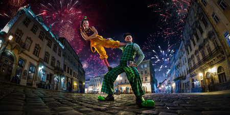 Night street circus performance whit clown, juggler. Festival city background. fireworks and Celebration atmosphere. Wide engle photoの写真素材