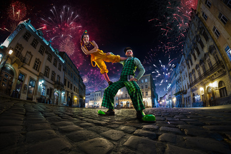 Night street circus performance whit clown, juggler. Festival city background. fireworks and Celebration atmosphere. Wide engle photoの写真素材