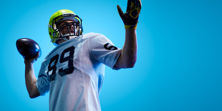American football sportsman player on blue gradient background. Sport advertisingの写真素材