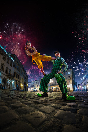 Night street circus performance whit clown, juggler. Festival city background. fireworks and Celebration atmosphere. Wide engle photoの写真素材