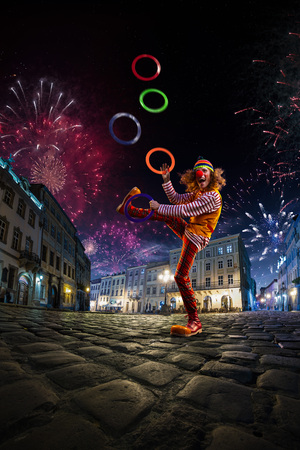 Night street circus performance whit clown, juggler. Festival city background. fireworks and Celebration atmosphere.の写真素材