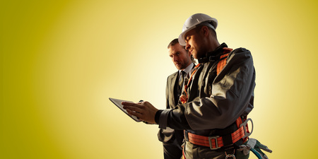 Windmill engineer and businessman planing new ecology project. they standing and looking in tablet. Color backgroundの写真素材