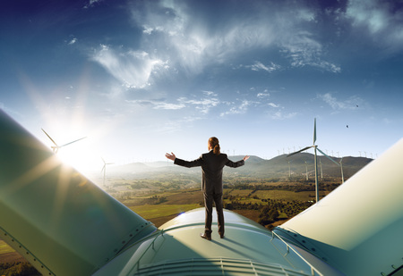 Happy businessman feel success after good work. He standing a top of windmill and looking beautiful sunset landscapeの写真素材