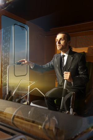 businessman operator crane in action . He sit a top in crane cabin and working. Around beautiful sunsetの写真素材