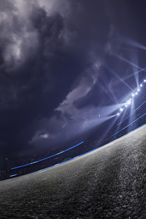 Night emprty stadium. Around Illuminated shiny spotlight. Dramatic clouds Atmosphere. Wide angleの写真素材