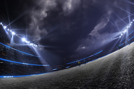 Night emprty stadium. Around Illuminated shiny spotlight. Dramatic clouds Atmosphere. Wide angleの写真素材