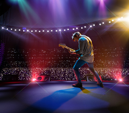 Rock star celebrity on the main stage big music festival. Aroun full stadium of spectators. fans are holding flashlightsの写真素材