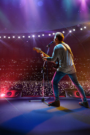 Rock star celebrity on the main stage big music festival. Aroun full stadium of spectators. fans are holding flashlightsの写真素材