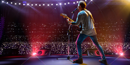 Rock star celebrity on the main stage big music festival. Aroun full stadium of spectators. fans are holding flashlightsの写真素材