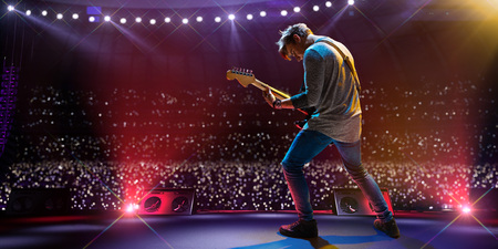 Rock star celebrity on the main stage big music festival. Aroun full stadium of spectators. fans are holding flashlightsの写真素材