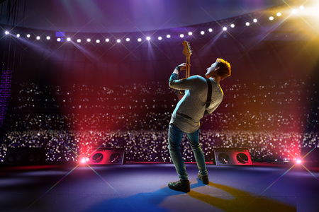 Rock star celebrity on the main stage big music festival. Aroun full stadium of spectators. fans are holding flashlightsの写真素材