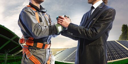 engineer and businessman shake hands. Around wind solar station and beautiful landscapeの写真素材