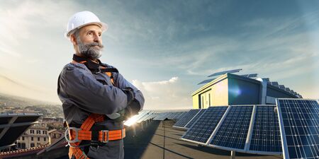 Happy engineer feel success after good work. He standing near solar station and looking beautiful sunset landscapeの写真素材