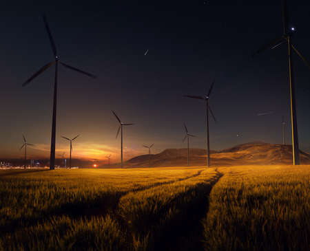 Beautiful sunset field with wind mill generators. big city in backgroundの写真素材