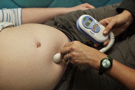 Midwife listening to the heartbeats of an unborn