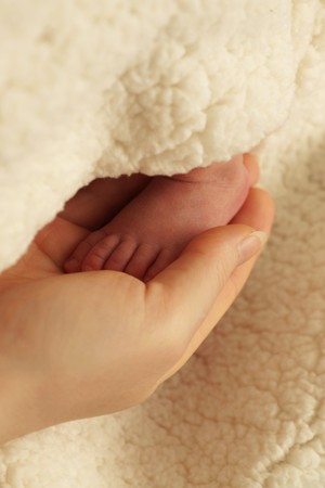 Sweet baby foot in loving mother handの写真素材