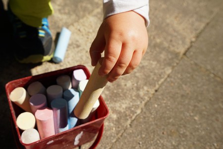 Children's hands and colorful chalk on a playgroundの写真素材