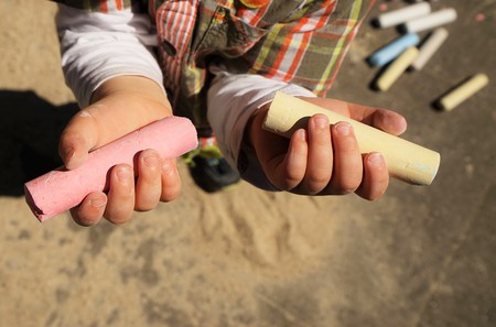 Children's hands and colorful chalk on a playgroundの写真素材