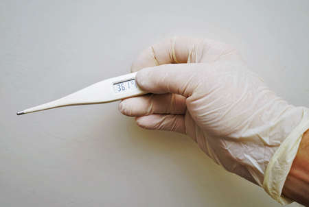 Doctor hold medical digital thermometer in hand on white backgroundの写真素材