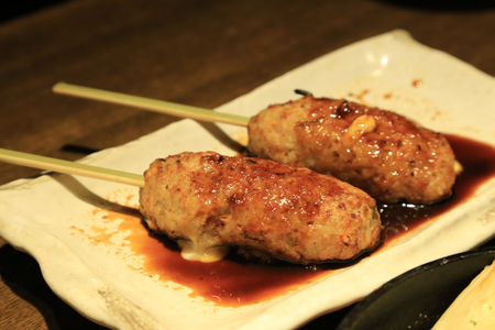 Tsukune filled with cheese serve with special sauce on white plateの写真素材