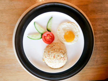 Fried egg with tomato and cucumber in a plate on the tableの写真素材