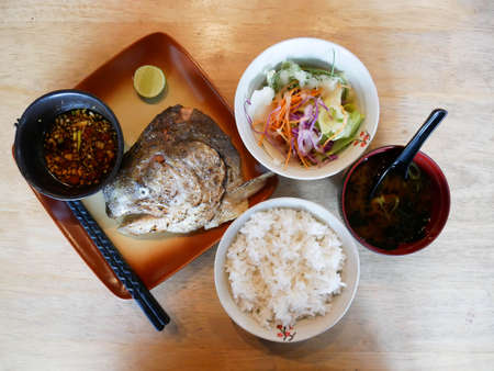 Fried tilapia fish with rice and soup on wooden tableの写真素材