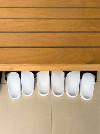 Close-up of a row of white ceramic sauna slippers.