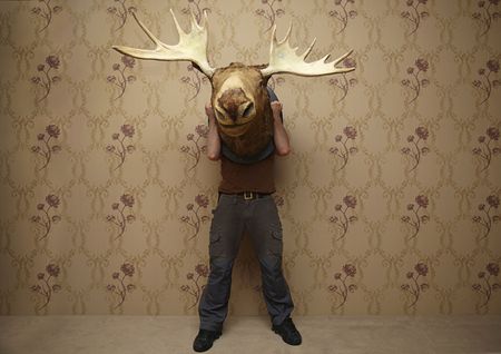 man is hiding behinde a moose headの写真素材