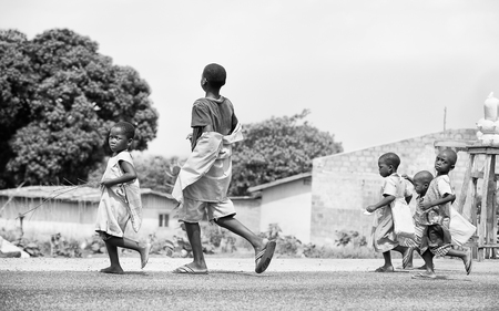 PORTO-NOVO, BENIN - MAR 8, 2012: Unidentified Beninese children run in the street. People of Benin suffer of poverty due to the difficult economic situation.のeditorial素材