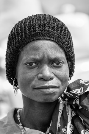 PORTO-NOVO, BENIN - MAR 8, 2012: Unidentified Beninese woman in a black hat portrait. People of Benin suffer of poverty due to the difficult economic situation.のeditorial素材