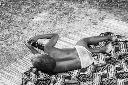 PORTO-NOVO, BENIN - MAR 8, 2012: Unidentified Beninese little boy plays on the ground. People of Benin suffer of poverty due to the difficult economic situation.のeditorial素材
