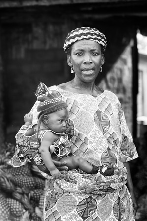 PORTO-NOVO, BENIN - MAR 8, 2012: Unidentified Beninese little beautiful child in a blue hat on his mother arms. People of Benin suffer of poverty due to the difficult economic situation.のeditorial素材