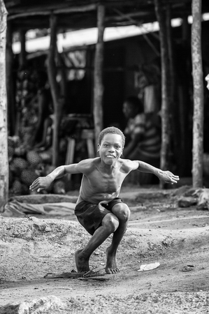 PORTO-NOVO, BENIN - MAR 8, 2012: Unidentified Beninese little boy jumps imitatiing a duck. People of Benin suffer of poverty due to the difficult economic situation.のeditorial素材