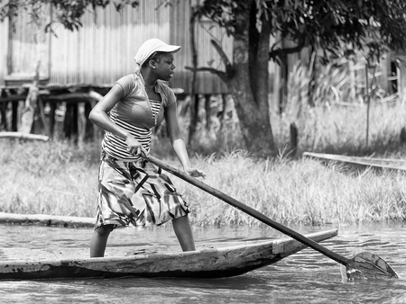 PORTO-NOVO, BENIN - MAR 9, 2012: Unidentified Beninese  woman sails a wooden boat. People of Benin suffer of poverty due to the difficult economic situation.のeditorial素材