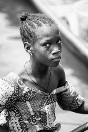 PORTO-NOVO, BENIN - MAR 9, 2012: Unidentified Beninese woman in a wooden boat. People of Benin suffer of poverty due to the difficult economic situation.のeditorial素材