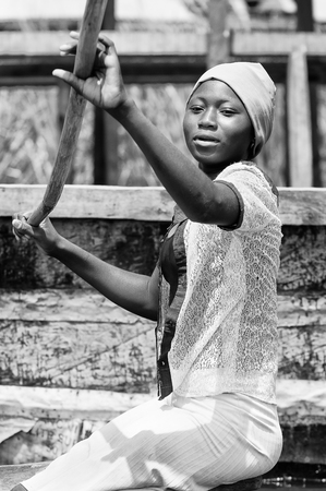 PORTO-NOVO, BENIN - MAR 9, 2012: Unidentified Beninese girl woman in a wooden boat. People of Benin suffer of poverty due to the difficult economic situationのeditorial素材