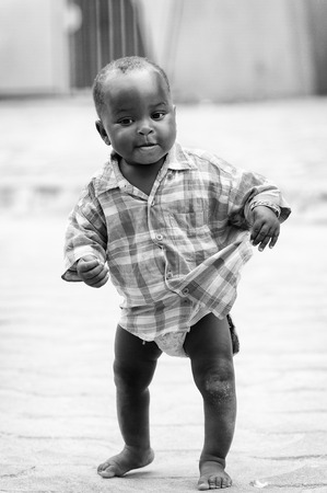 PORTO-NOVO, BENIN - MAR 10, 2012: Unidentified Beninese cute little boy in checkered shirt walks in...