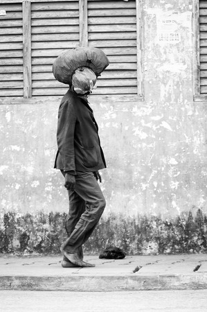PORTO-NOVO, BENIN - MAR 10, 2012: Unidentified Beninese man walks with a stuff on his head. People of Benin suffer of poverty due to the difficult economic situationのeditorial素材