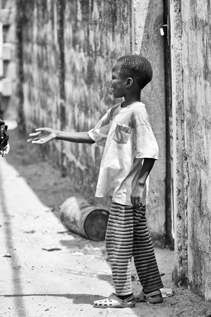 PORTO-NOVO, BENIN - MAR 10, 2012: Unidentified Beninese local boy walks in the street People of Benin suffer of poverty due to the difficult economic situationのeditorial素材
