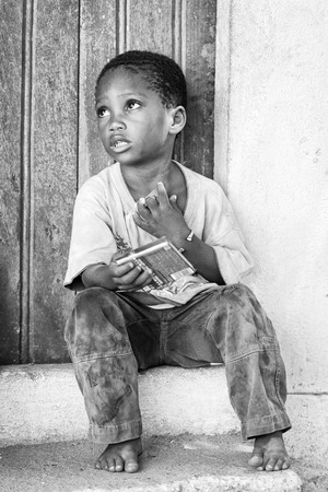 KARA, TOGO - MAR 9, 2013: Unidentified Togolese boy sits at the porch of a house. Children in Togo suffer of poverty due to the unstable econimic situationのeditorial素材