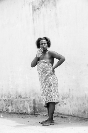 KARA, TOGO - MAR 9, 2013: Unidentified Togolese woman stays near a house. People in Togo suffer of poverty due to the unstable econimic situationのeditorial素材
