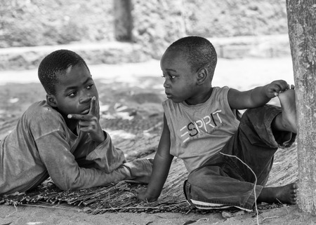 KARA, TOGO - MAR 9, 2013: Unidentified Togolese boys sit near a tree. Children in Togo suffer of poverty due to the unstable econimic situationのeditorial素材